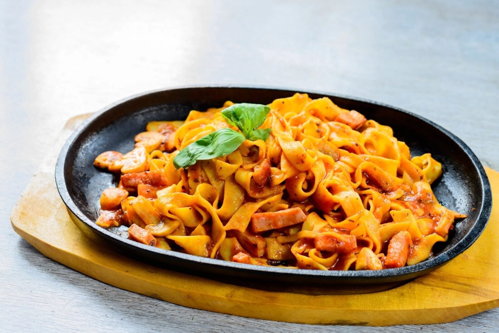 A sizzling plate of fresh pasta on a wooden board